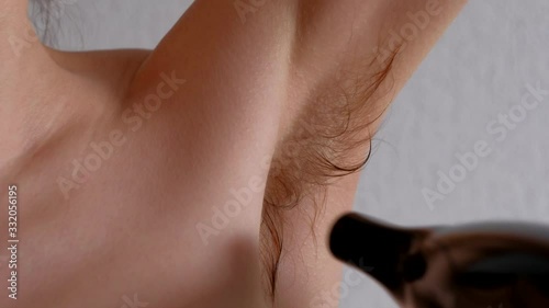 Bodypositive concept, feminism, female with raised arms dry wet and long armpit hair by dryer. Close-up.