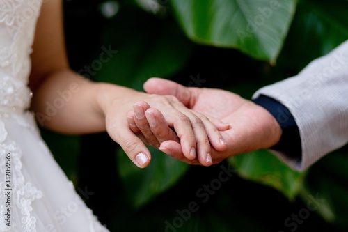 Groom holding bride hands in the garden.