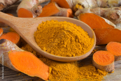 Turmeric powder and fresh turmeric (curcumin) on wooden background,Used for cooking.