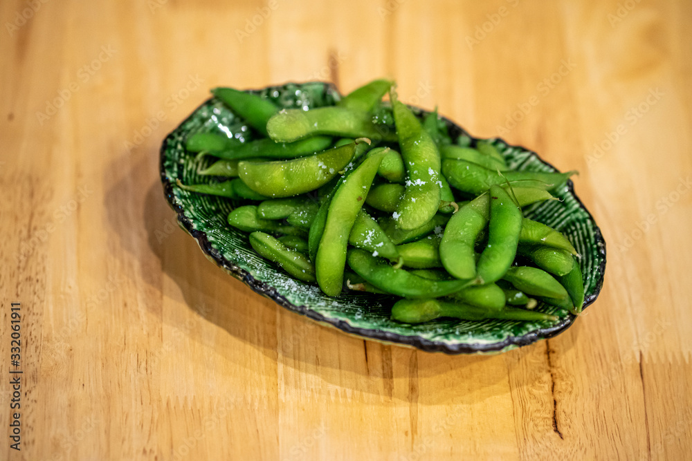 Fresh steamed edamame sprinkled with sea salt on Wooden table background Fresh steamed edamame sprinkled with sea salt on Wooden table background