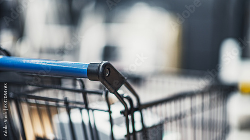 Supermarket aisle with shopping cart in blurred department store background.