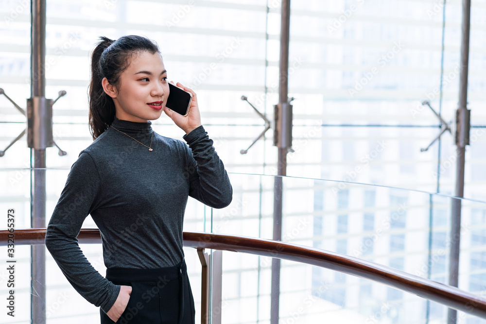 A young business woman uses a mobile phone in the building A young business woman uses a mobile phone in the building