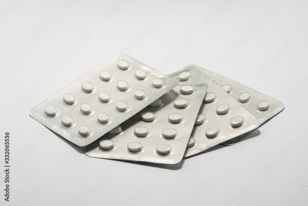 Foil packets of white tablet pills medication on plain white background. Cure and treatment concept. Foil packets of white tablet pills medication on plain white background. Cure and treatment concept.