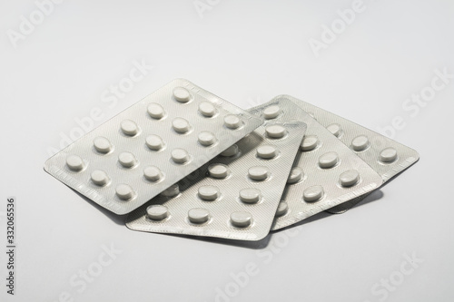 Foil packets of white tablet pills medication on plain white background. Cure and treatment concept.