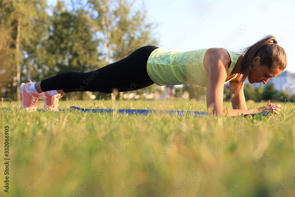 Athletic woman doing plank exercise outdoor. Work out concept. - obrazy, fototapety, plakaty 