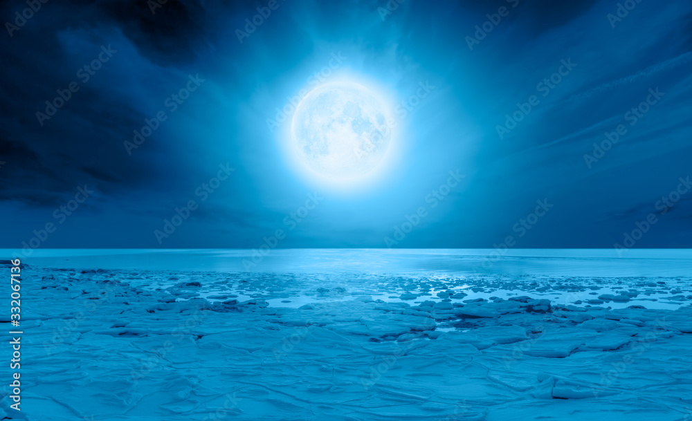 Night sky with full moon in the clouds  - Ice on the ocean shore at night 