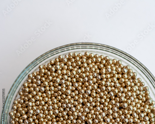 Close up of little golden balls in a clear transparent bowl.
