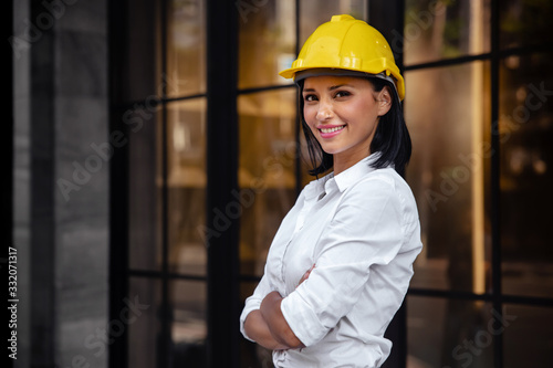 Portrait of a Confident Construction Engineer Woman. Smiling and Looking at Camera. Standing in front of the Modern Office Building photo