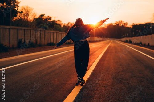 Young woman skateboarding at sunset