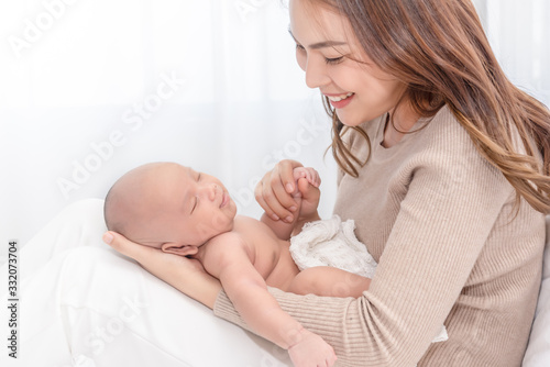 Close up beautiful young asian mother holding her newborn one month baby sleep on herlap. Healthcare and medical love asia woman lifestyle mother's day concept.