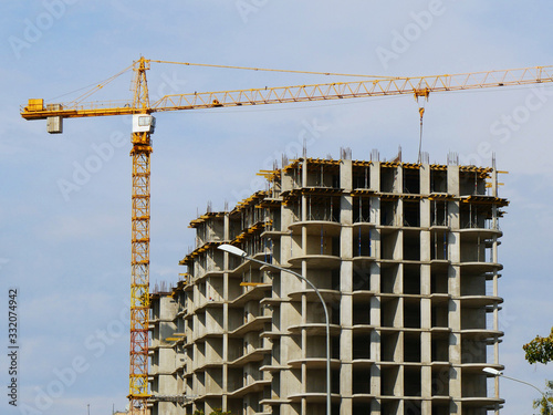 Crane near building. Concrete building under construction.