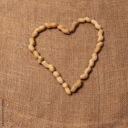 Peanuts arranged to form a heart. Rustic background of raw yuta canvas. photo