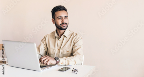 Young handsome man using laptop at home, Businessman or student working online on computer indoors, Freelance, online marketing, distance education, home work and technology concept