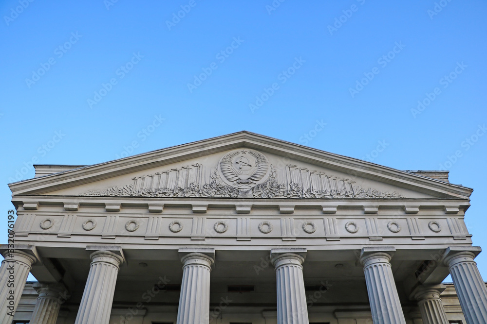 Old Soviet building with columns against the blue sky.