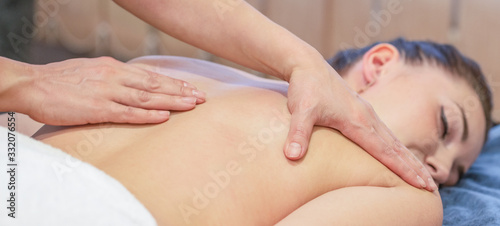 Hands of massage therapist doing massage on back of young girl