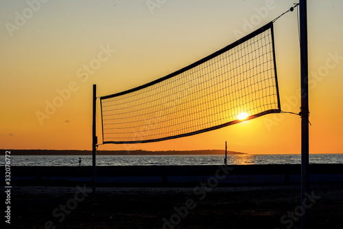 Sillhouette of a volleyball net against sunset on the beach