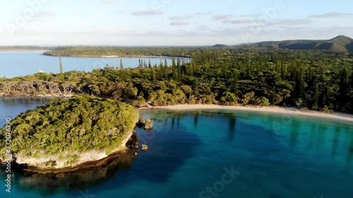 Surrounded by plants of coconut trees and column pines, the beach of Kanumera bay is ideal for snorkeling in the scenario of the Isle of Pines in New Caledonia. photo