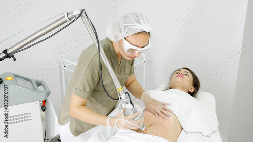 professional therapist makes laser hair removal procedure on attractive lady belly in medical beauty clinic
