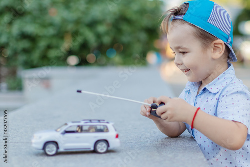 a small boy plays with a toy car on radio control holding a remote control