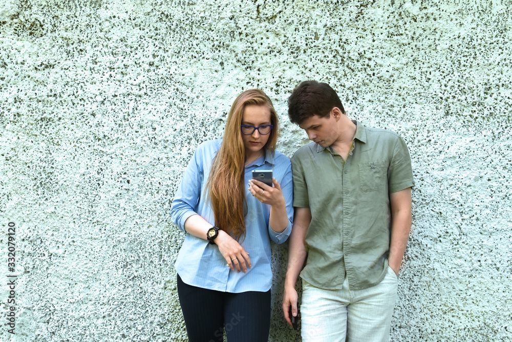 A pair of young people look attentively at the smartphone screen A pair of young people look attentively at the smartphone screen