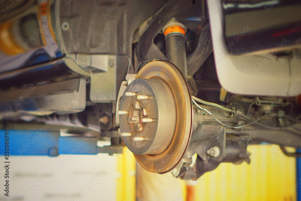 car brake part at garage,car brake disc without wheels.Disk brake and car disk brake system service concept - Car disk brake pad replacement service by hand of mechanic man in car garage.Close up. car brake part at garage,car brake disc without wheels.Disk brake and car disk brake system service concept - Car disk brake pad replacement service by hand of mechanic man in car garage.Close up.