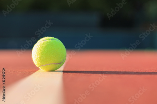 Bright greenish yellow tennis ball on the line. © ty