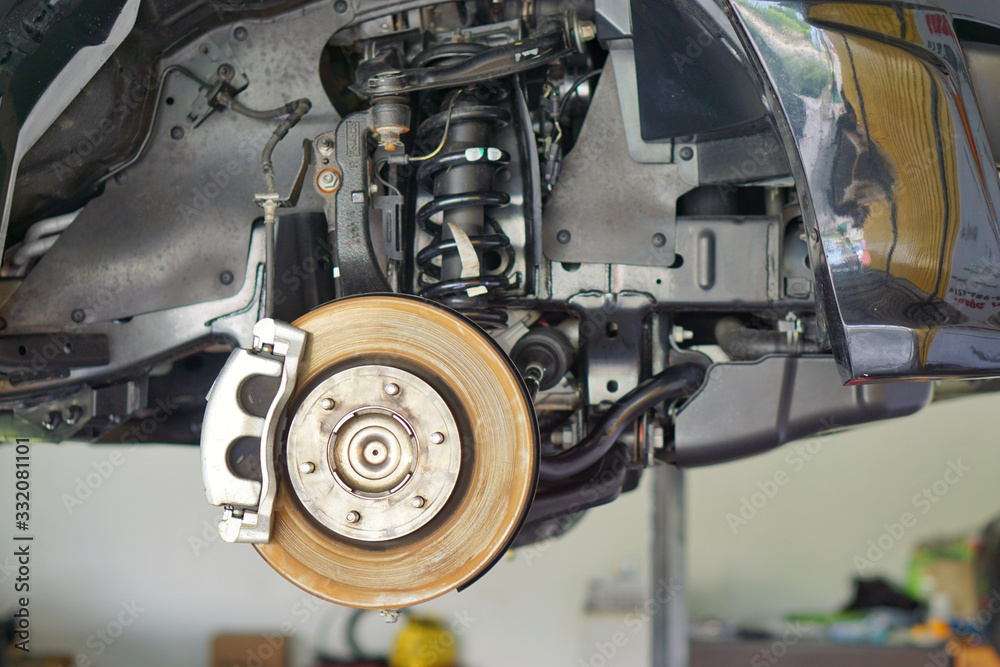 car brake part at garage,car brake disc without wheels.Disk brake and car disk brake system service concept - Car disk brake pad replacement service by hand of mechanic man in car garage.Close up. car brake part at garage,car brake disc without wheels.Disk brake and car disk brake system service concept - Car disk brake pad replacement service by hand of mechanic man in car garage.Close up.