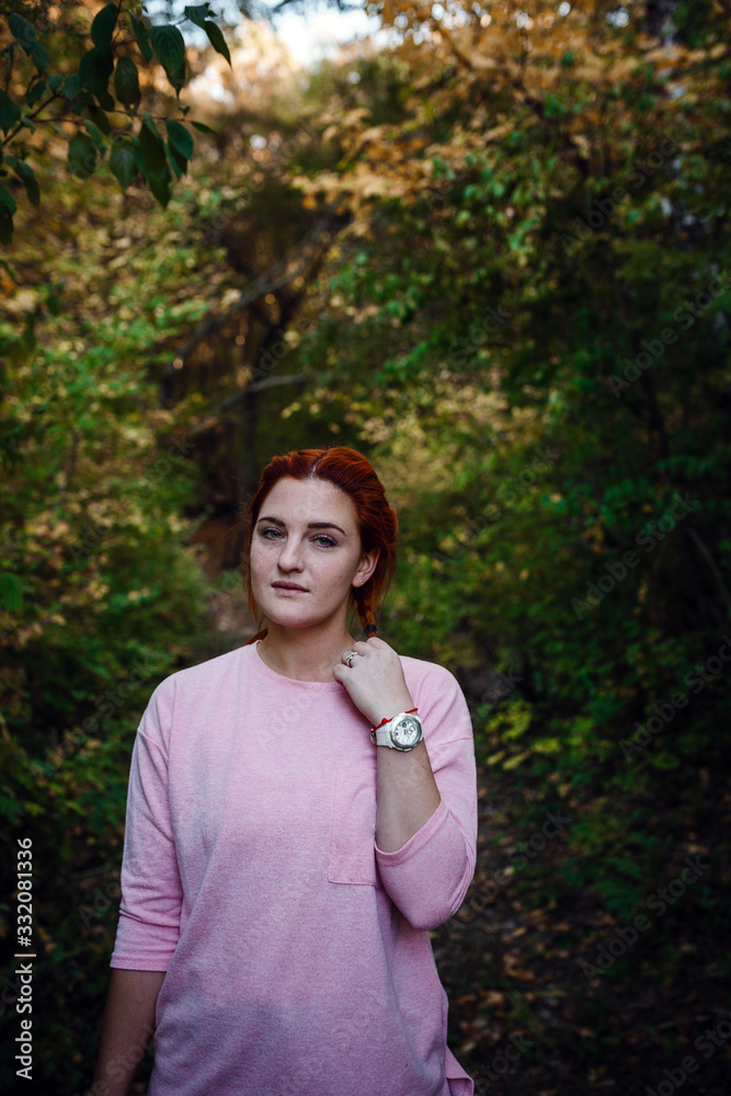 Beautiful young red-haired woman in the autumn forest