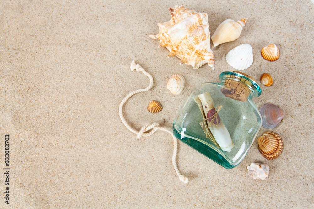 message in a bottle, sea shells and pebbles on sand