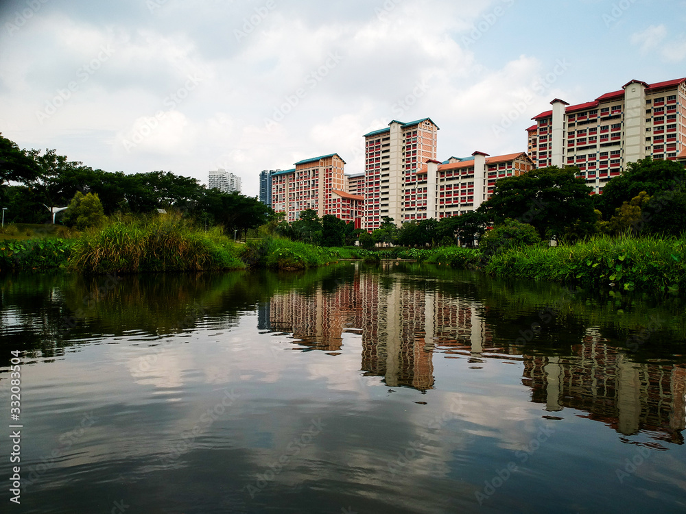 reflections of residential buildings in the pond of a neighborhood park