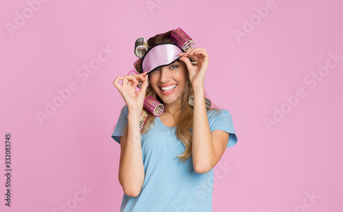 Housewife with curlers removes a sleep mask © Prostock-studio