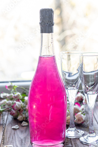 Sparkling brilliant raspberry drink. Champagne in two glasses stands on a wooden table with ice. For flowers and a garland.
