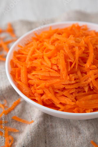 Shredded carrots in a white bowl, side view. Close-up.