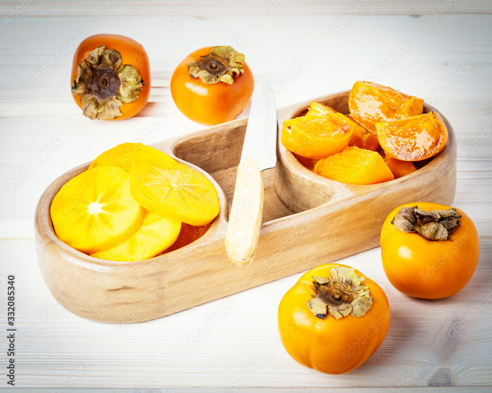 Persimmon, walnuts, cashew nuts, almonds on wooden plates