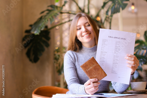 Young girl holding passport and visa application, sitting at cabinet.