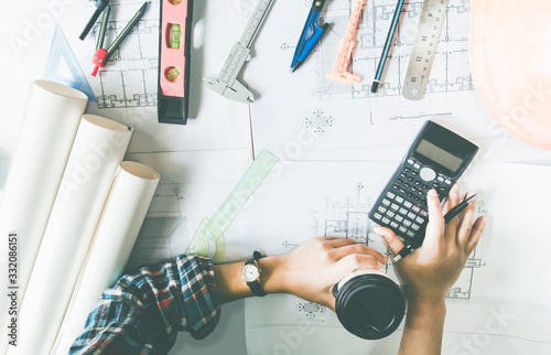 Concept architects, Hand of asian young man engineering use calculator for calculation number of structural materials writing On the desk with a blueprint in the office.