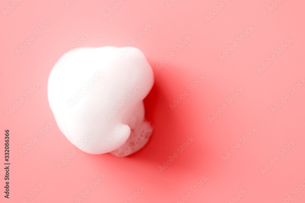 White foam smudge from soap, shampoo or cleanser on pink background with selective focus. Close-up, macro White foam smudge from soap, shampoo or cleanser on pink background with selective focus. Close-up, macro