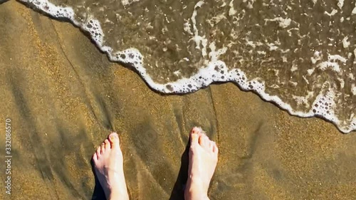 Wave and sand flows around the feet, top view slow motion