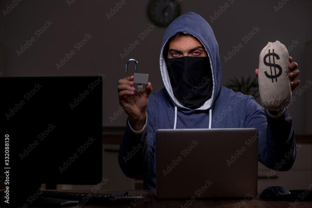 Male hacker hacking security firewall late in office Male hacker hacking security firewall late in office