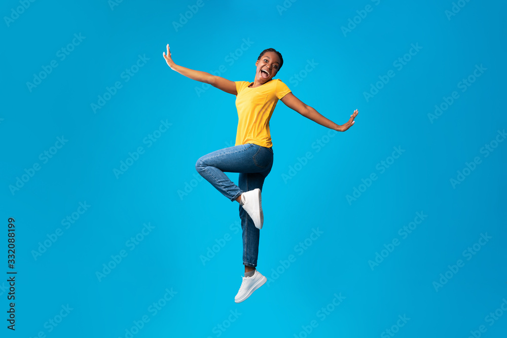 Positive African American Girl Jumping Posing Over Blue Background Positive African American Girl Jumping Posing Over Blue Background