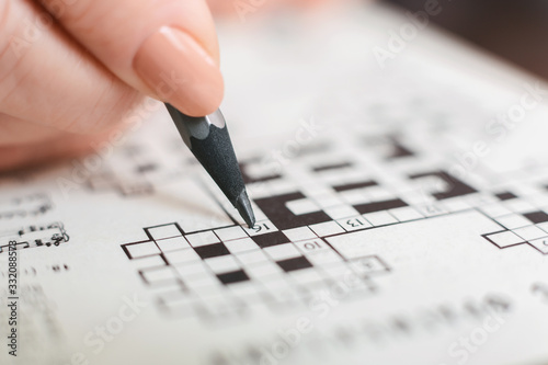 Senior woman completing crossword at home, close up photo