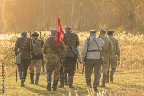 A group of red army soldiers with a red flag goes towards the forest. Historical reenactment