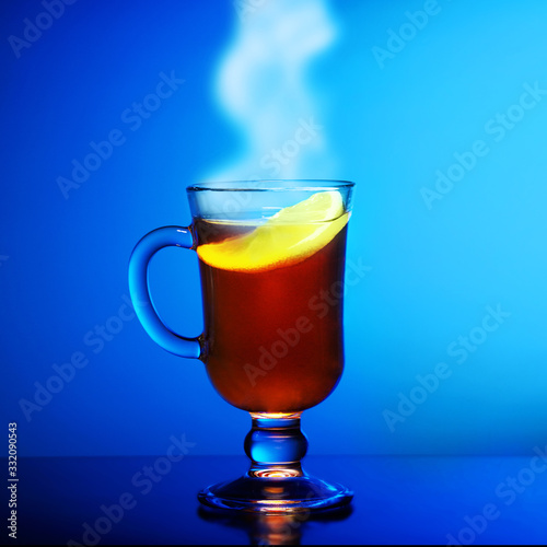 Cup of hot steaming tea with lemon on a blue background