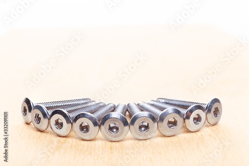 Hex head bolt screws thread on wooden table. Close up view photo