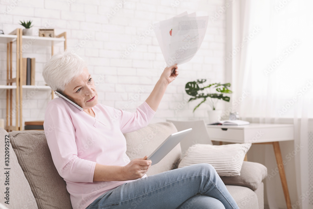 Disappointed senior lady reading document and talking by phone Disappointed senior lady reading document and talking by phone