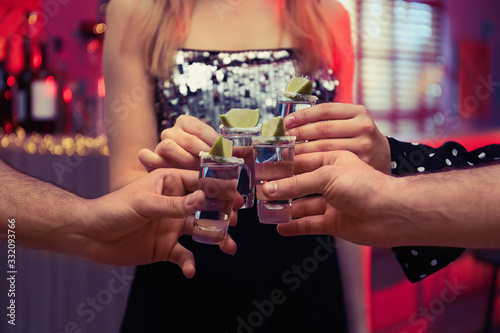 Young people toasting with Mexican Tequila shots in bar, closeup