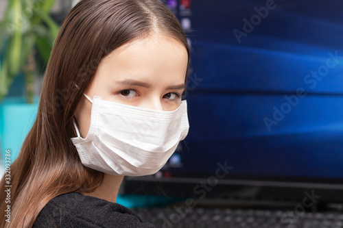 Quarantine and coronavirus danger. A young woman in an antibacterial mask works at a computer photo