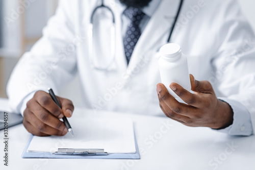 African general practitioner holding pills box and writing