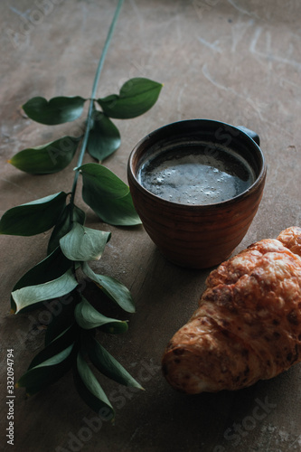 Cappuccino coffee and croissant on wooden background on the table. Perfect breakfast in the morning. Rustic candid style.
