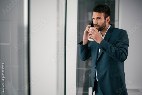  Businessman on his phone while on coffee break. Young handsome man having a call while drinking coffee. 